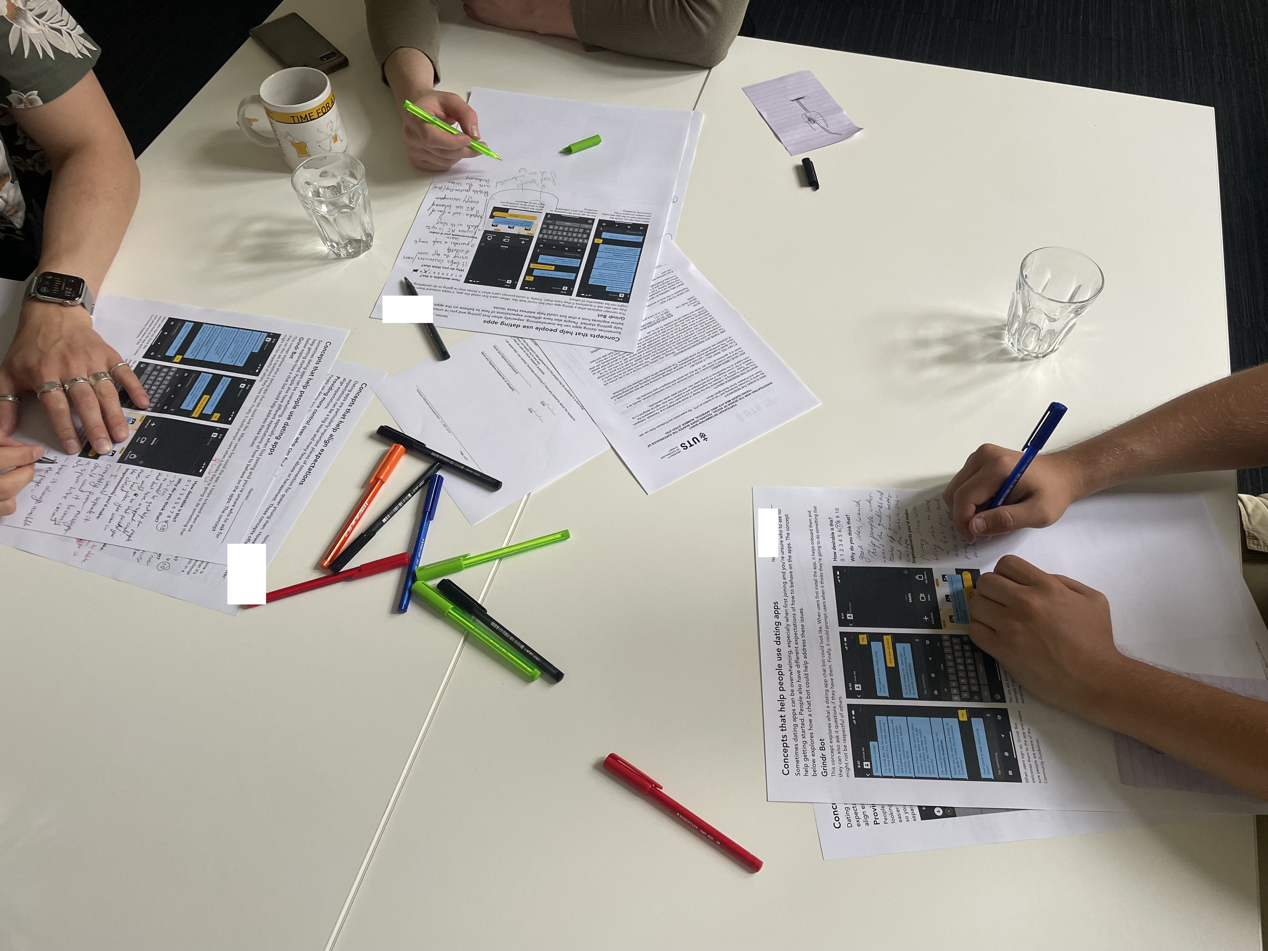 Looking down at a table that has evaluation worksheets on it. The hands of participants writing are visible.